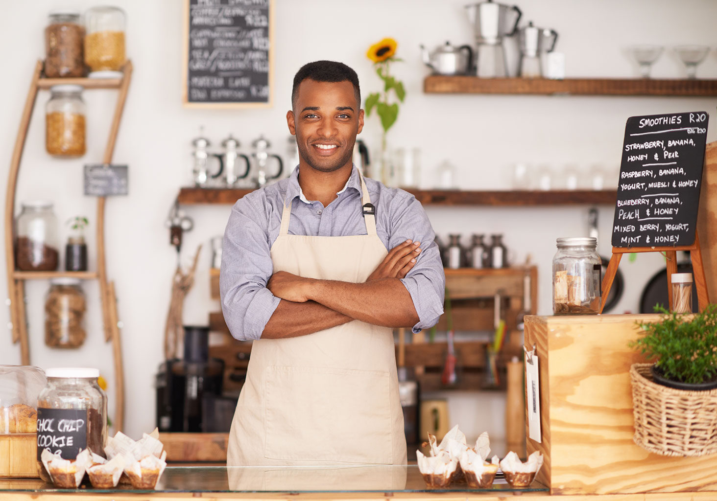 African American Business Owner Proudly Standing with Arms Crossed in His Cozy Coffee Shop, Flashing a Welcoming Smile